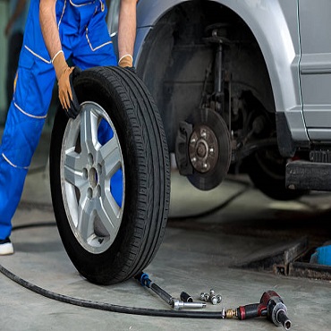 Technician installing a tire on a vehicle in a service bay
